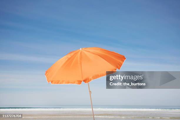 orange parasol on the beach against blue sky - sombrilla fotografías e imágenes de stock