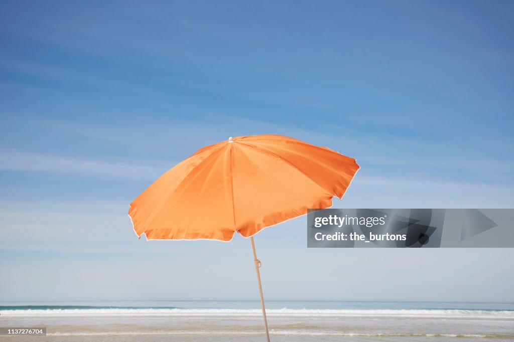 Orange parasol on the beach against blue sky