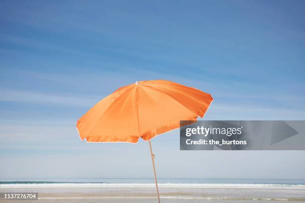 orange parasol on the beach against blue sky - sunshade stock pictures, royalty-free photos & images