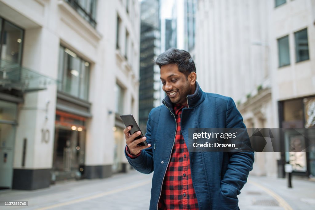 Indian businessman with smart phone, using mobile app.