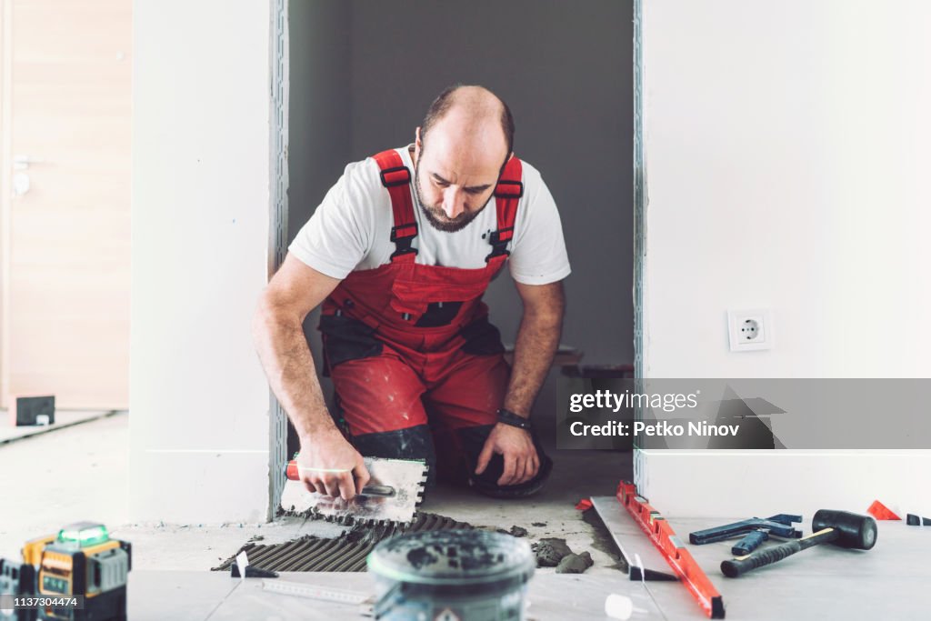Solador profesional que pone azulejos en el piso en nuevo apartamento