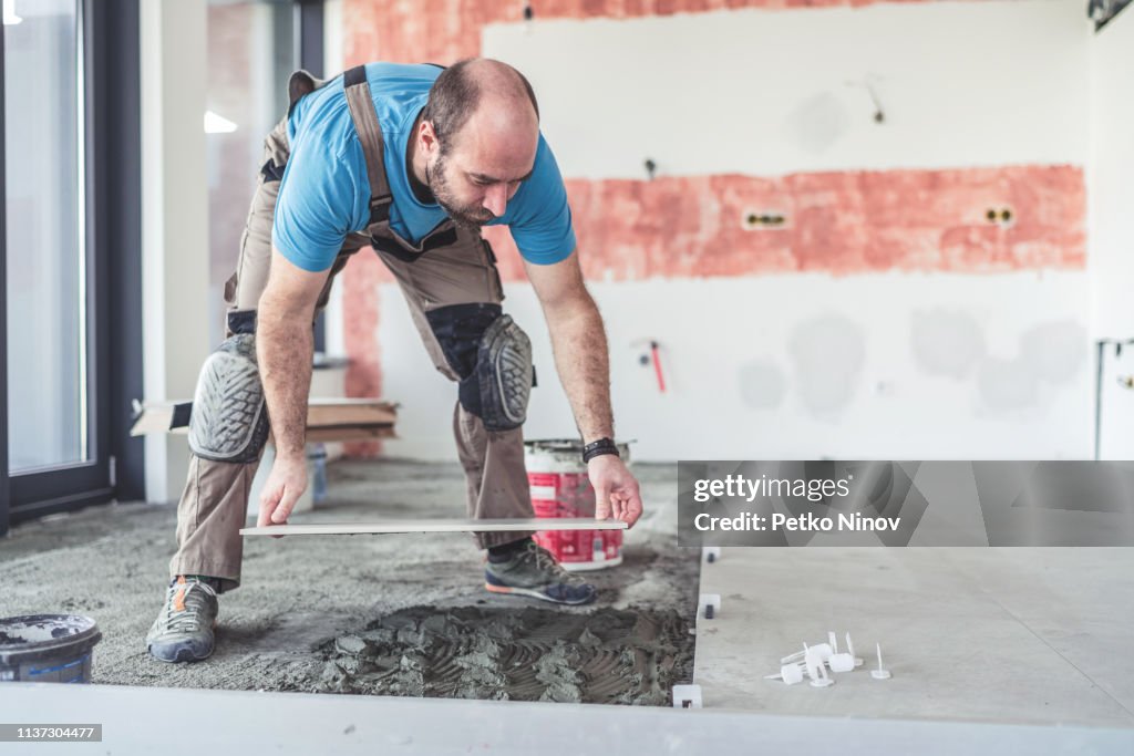 Azulejos de albañil poniendo baldosas en el suelo