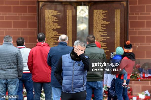 People gather in front of the Hillsborough memorial, outside of Liverpool Football Club's main stand at Anfield in Liverpool, north-west England, on...