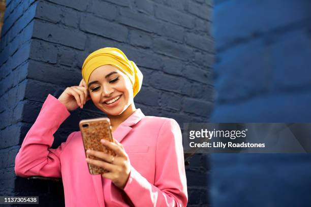 young muslim woman using phone - islam stock-fotos und bilder