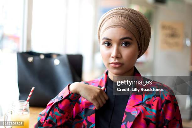 one young muslim woman sitting in cafe looking at camera - women with hijab stock pictures, royalty-free photos & images