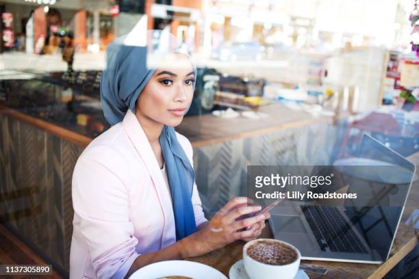 young muslim woman working in cafe - islam stock-fotos und bilder