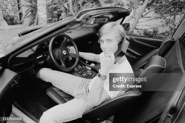 American actor Christopher Atkins speaking over a phone from a Ferrari car, UK, 24th November 1983.