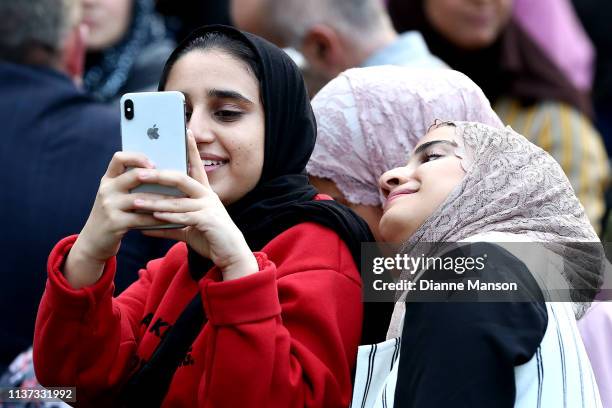 Girls play on their iphone ahead of the vigil at Forsyth Barr Stadium on March 21, 2019 in Dunedin, New Zealand. 50 people were killed, and dozens...