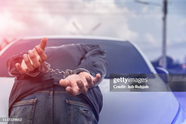 handcuffed criminal lying face-down in car park - handcuffs stock-fotos und bilder