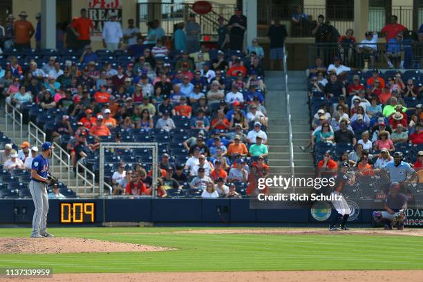 Pitcher Eric Hanhold of the New York Mets gets set to deliver a pitch as the pitch clock counts down during the ninth inning of a spring training...