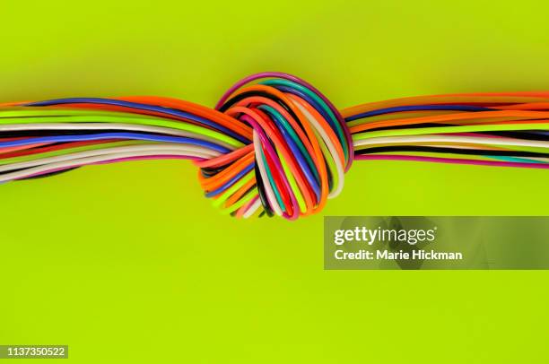 a knot made up of plastic strands on a neon yellow green background with copy space.. - würgen stock-fotos und bilder