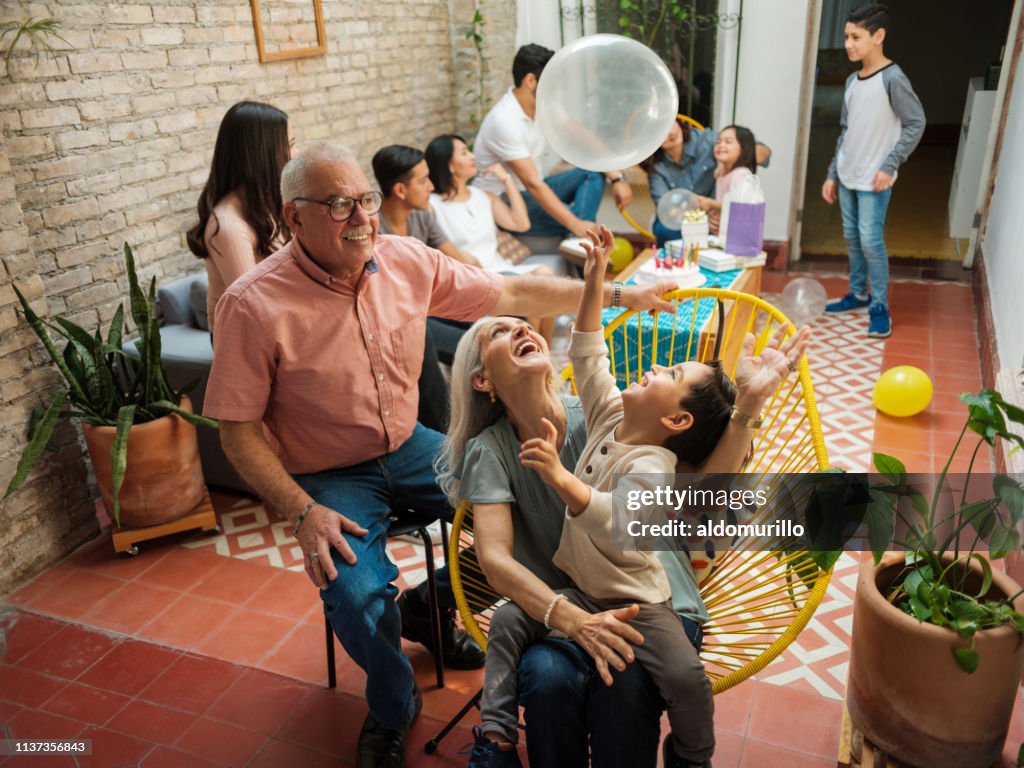 Glückliche mexikanische Großeltern und Enkel spielen mit Ballon