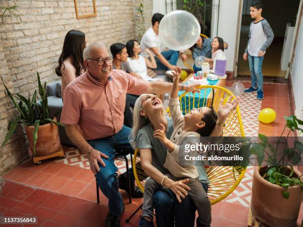 glückliche mexikanische großeltern und enkel spielen mit ballon - mexikanischer abstammung stock-fotos und bilder