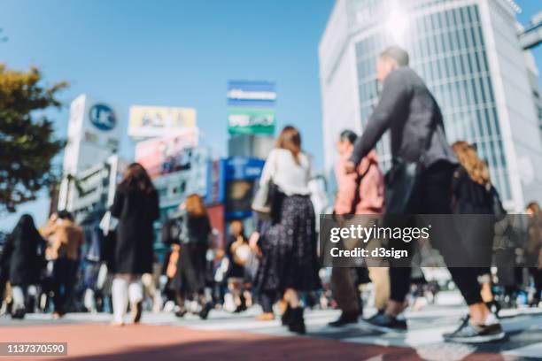 crowd of busy commuters crossing street in shibuya crossroad, tokyo - business man in crowd stock pictures, royalty-free photos & images