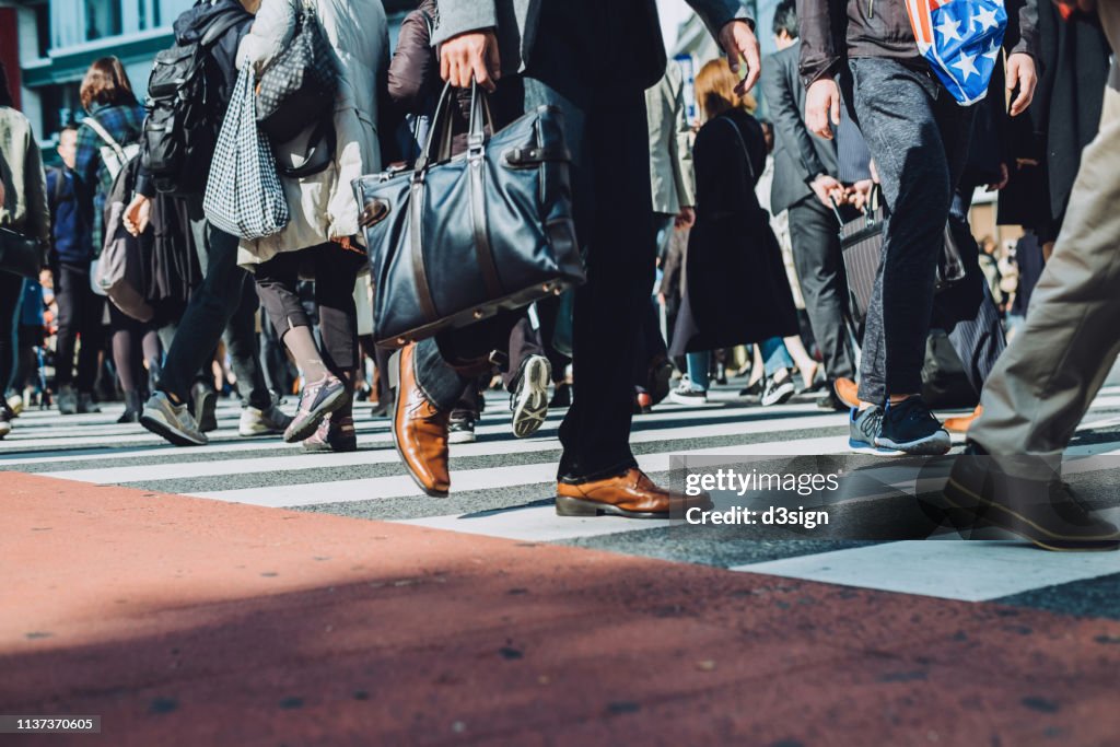 Low section view of a crowd of busy commuters crossing street in Shibuya crossroad, Tokyo