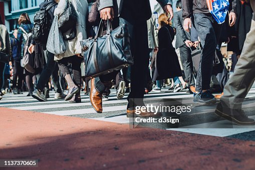 Low section view of a crowd of busy commuters crossing street in Shibuya crossroad, Tokyo Low section view of a crowd of busy commuters crossing street in Shibuya crossroad, Tokyo
