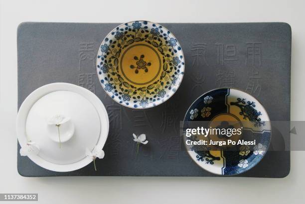 white gaiwan and a couple of floral cups of oolong tea on ardesia plate. - ardesia stock-fotos und bilder