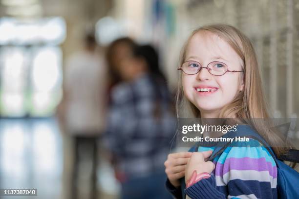 beautiful junior high school student with down syndrome smiles on her way to class - down syndrome girl stock pictures, royalty-free photos & images