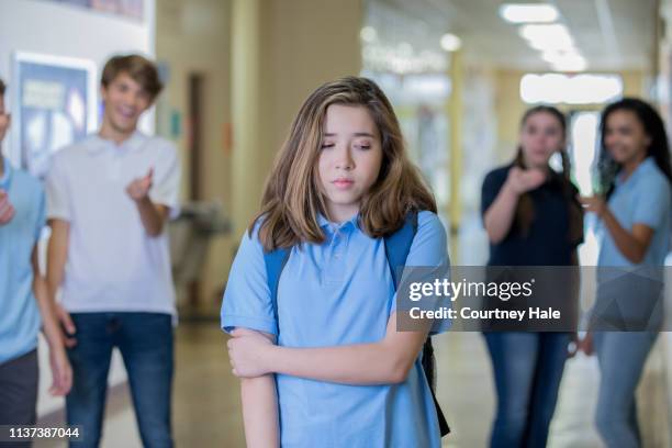 traurige junge teenager-mädchen geht in der schule flur, während bullies sie reizt - bully school stock-fotos und bilder