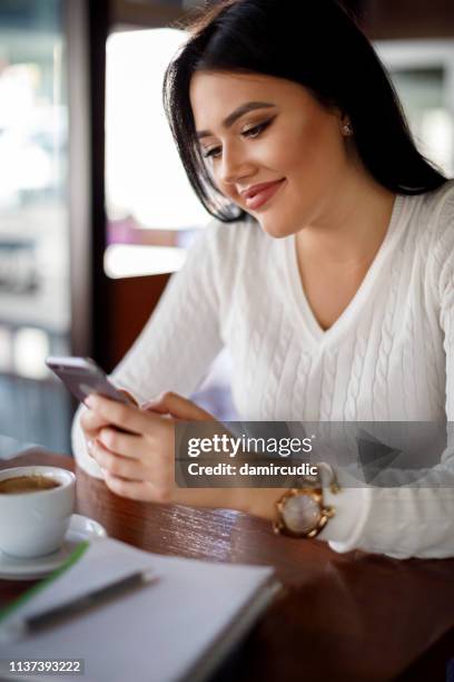 jonge vrouw met behulp van mobiele telefoon in een cafe - mobile phone edit stockfoto's en -beelden