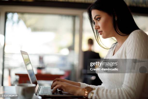 junge frau mit laptop in einem café - log in stock-fotos und bilder