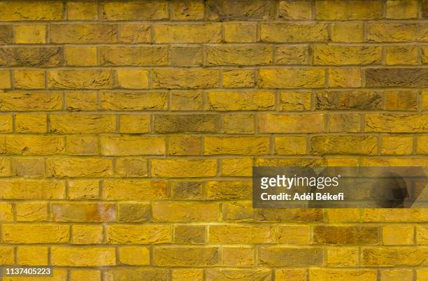 part of a brick wall - yellow wall stock-fotos und bilder
