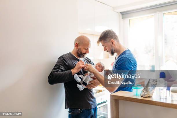 lgbtq familie-gay vaders - baby feeding stockfoto's en -beelden