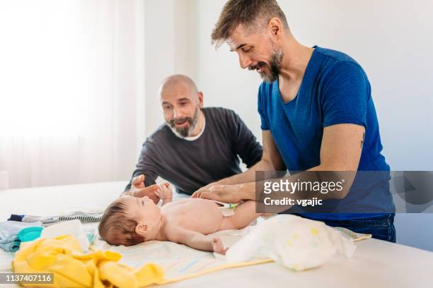famiglia lgbtq - papà gay - adult baby boy diaper change foto e immagini stock