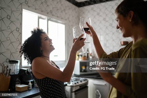 lesbische koppel op feestelijke toast in kitchen - wine cheers stockfoto's en -beelden