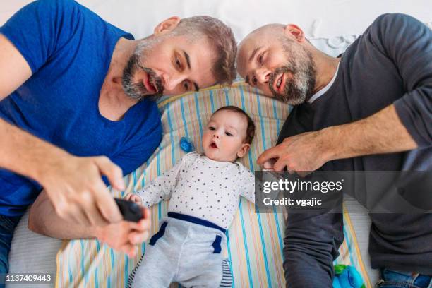 lgbtq family-gay dads in a bed - baby beard stock-fotos und bilder