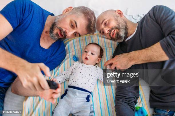 lgbtq family - gay dads in a bed - baby beard imagens e fotografias de stock