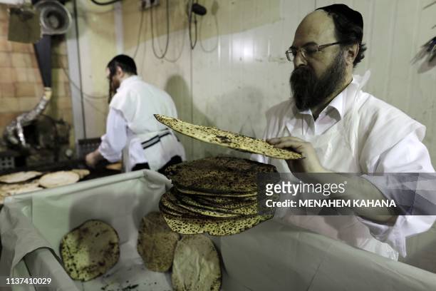 An Ultra-Orthodox Jewish man piles up freshly baked Matzoth at a bakery in the central Israeli city of Bnei Brak, on April 15, 2019. - Religious Jews...