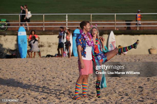 Young couple dress in bright colours in solidarity with OneWave at sunrise on Bondi Beach on March 22, 2019 in Sydney, Australia. Surfers gather to...