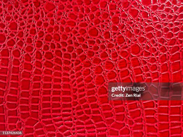 snake skin pattern on a vibrant red plastic material - schlangenleder stock-fotos und bilder