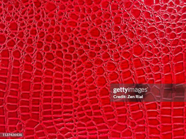 snake skin pattern on a vibrant red plastic material - snakeskin stock pictures, royalty-free photos & images