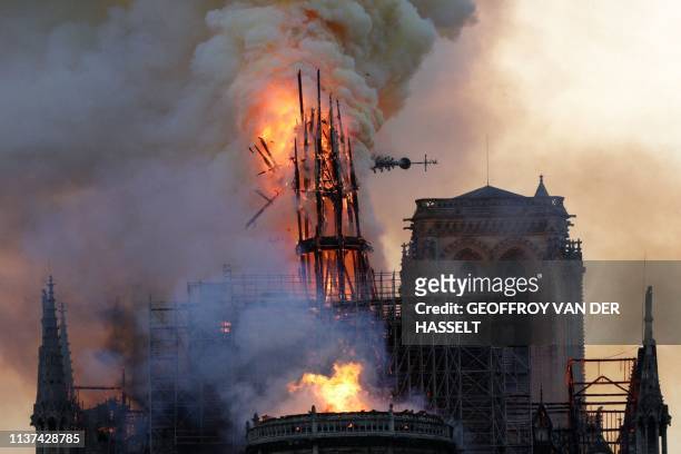 The steeple and spire collapses as smoke and flames engulf the Notre-Dame Cathedral in Paris on April 15, 2019. A huge fire swept through the roof of...