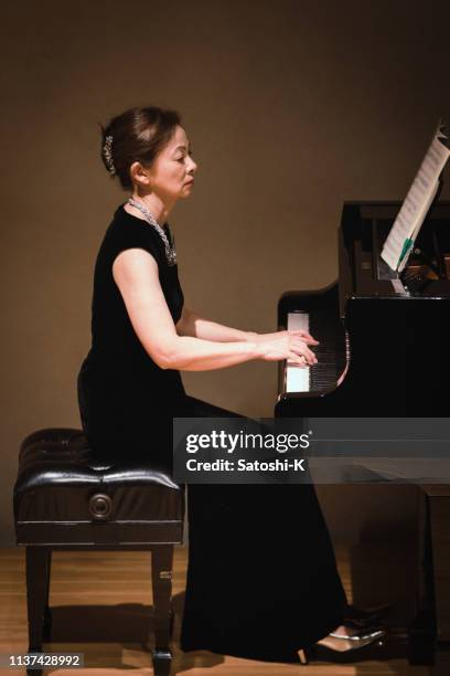 woman playing piano at classical music concert - asian pianist stock pictures, royalty-free photos & images