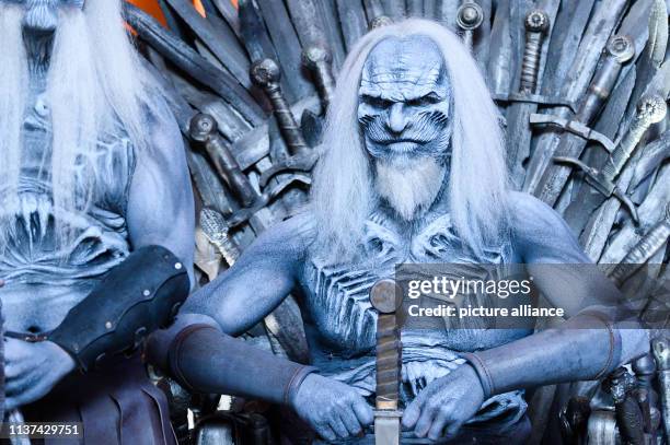 April 2019, Hamburg: A man dressed up as a "White Wanderer", known from the fantasy series "Game of Thrones", sits in a cinema on a throne in the...