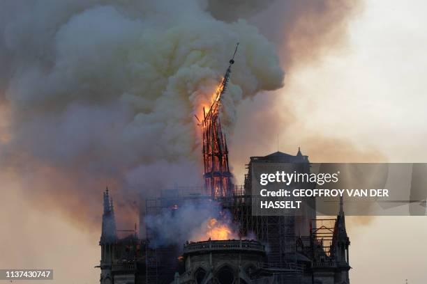 The steeple and spire engulfed in flames collapses as the roof of the Notre-Dame de Paris Cathedral burns on April 15, 2019 in Paris. A colossal fire...