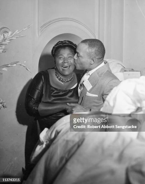 Chicago Defender publisher John H. Sengstacke kisses the cheek of noted gospel singer Mahalia Jackson , at an unidentified event, Chicago, IL, mid...