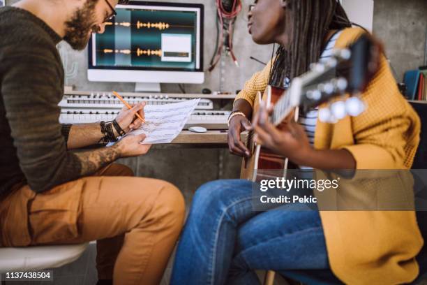 creative pareja escribiendo canción en el estudio - compositor fotografías e imágenes de stock