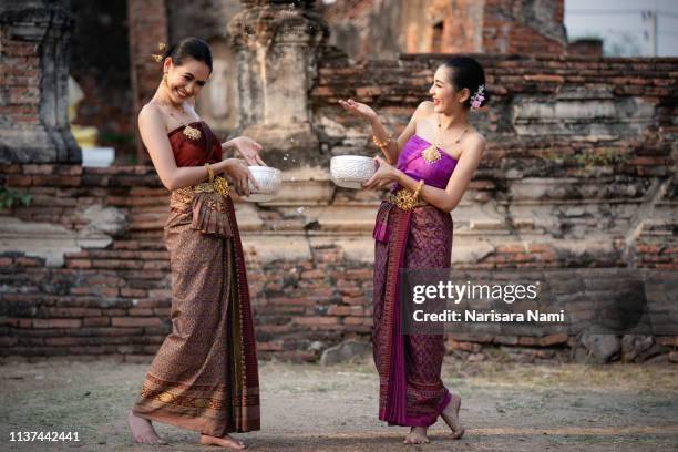 songkran festival in thailand. happy thai girls in thailand cultural costume splash the water during thai new year festival - fancy dress costume imagens e fotografias de stock