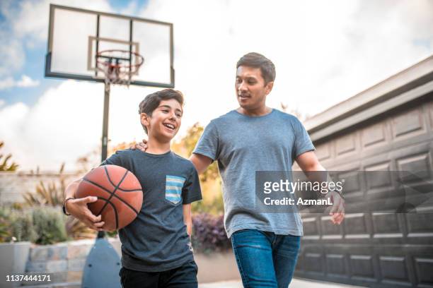 pai e filho após o fósforo de basquetebol na jarda traseira - bola de basquete - fotografias e filmes do acervo