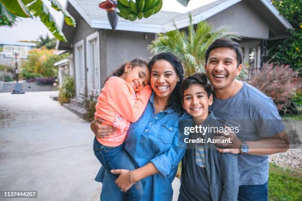 ritratto di famiglia felice contro casa - mixed race person foto e immagini stock