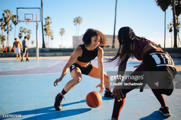 deux jeunes femmes jouant le streetball à venise, californie - venice beach photos et images de collection