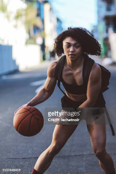 Young woman practicing streetball while walking the streets of Venice, California