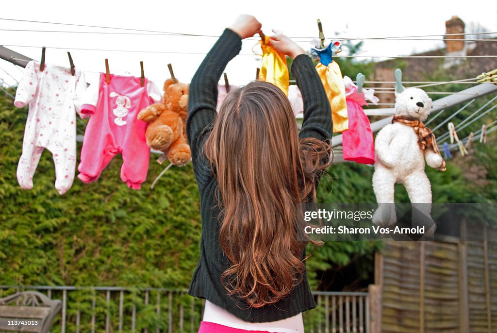 Girl pegging dolls clothes on the line