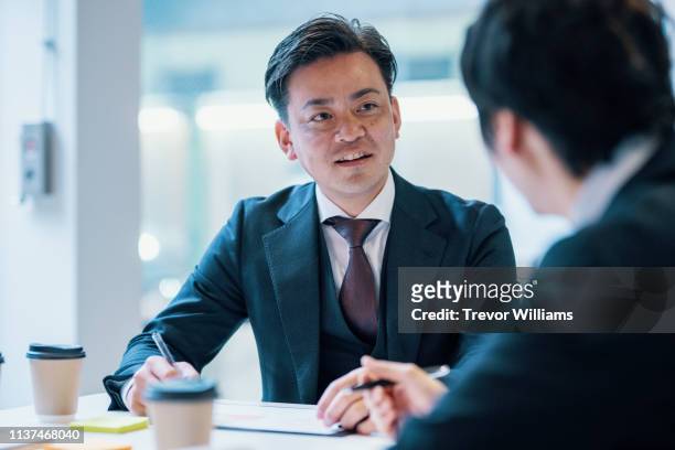 mid adult businessman meeting with a client in a corporate office - ビジネス　男性　日本人 ストックフォトと画像