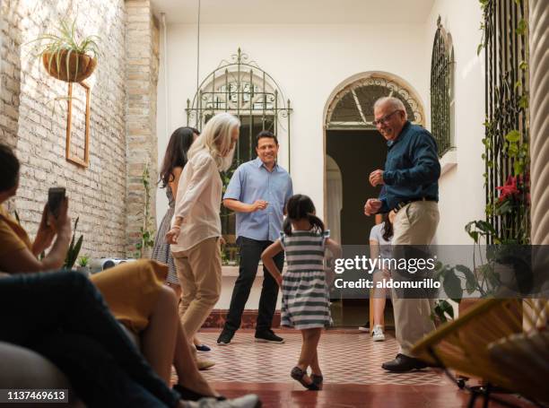 mexican family smiling at little girl dancing - traditional home interior stock pictures, royalty-free photos & images