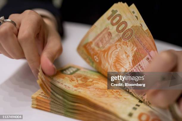 An employee counts Hong Kong one-thousand dollar banknotes at the Hang Seng Bank Ltd. Headquarters in Hong Kong, China, on Tuesday, April 16, 2019....